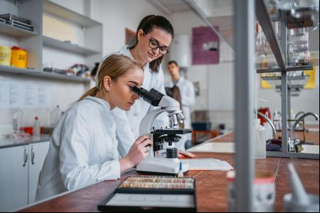 Una estudiante observando microorganismos a través de un microscopio